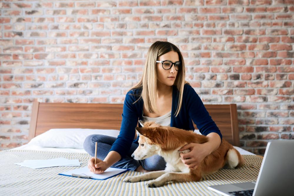 woman sat on bed with cross bread dog reading paperwork